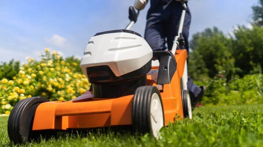 Image of lawnmower being used over green grass. 