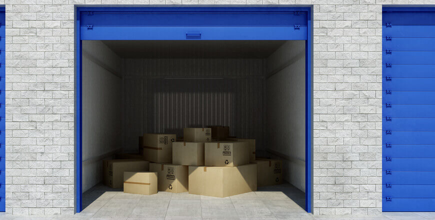 Image of a storage unit with blue shutters packed with cardboard boxes.