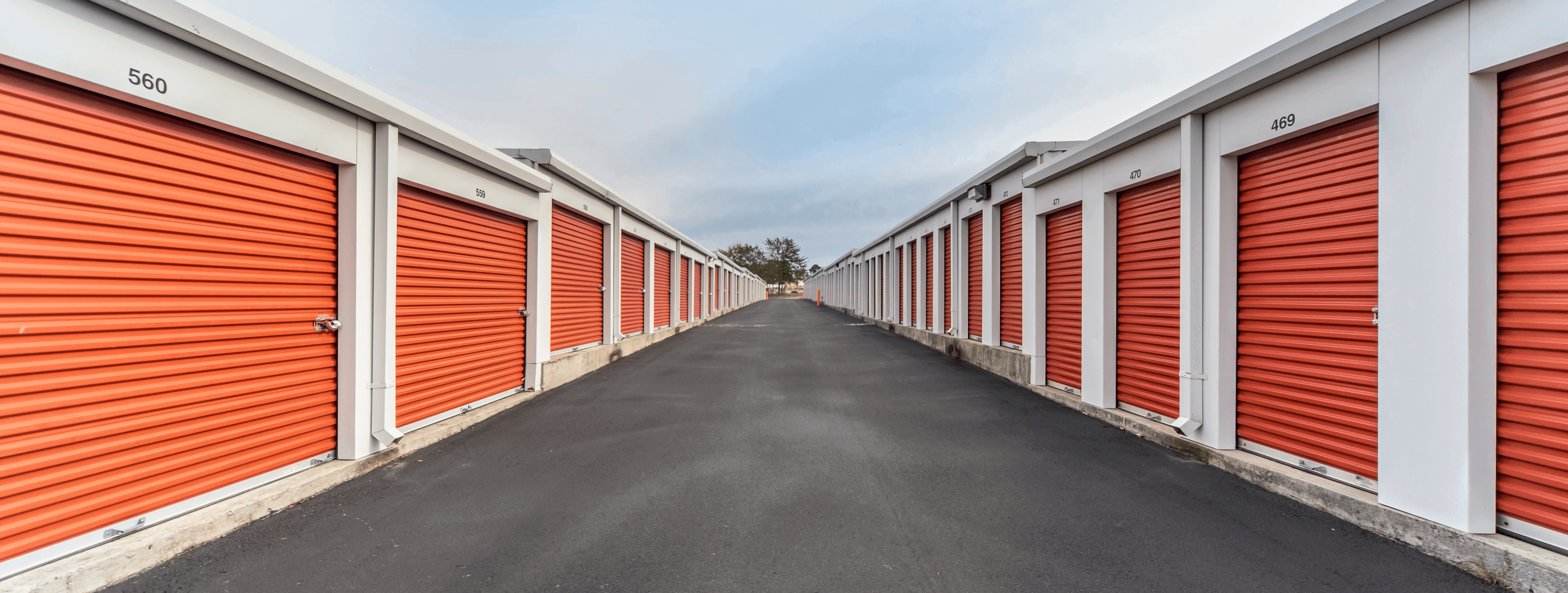 An outdoor shot of a row of self storage units with orange doors.