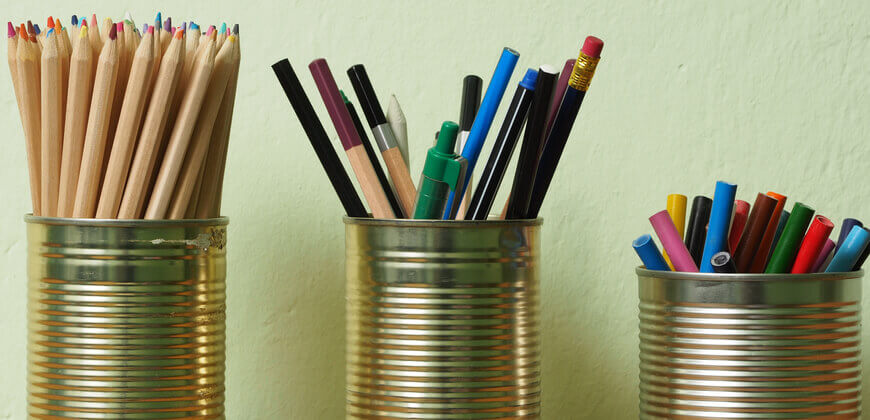 Image of pencils and crayons stored in tin cans. 