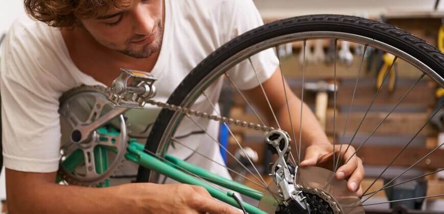 Image of man maintaining bicycle wheel. 
