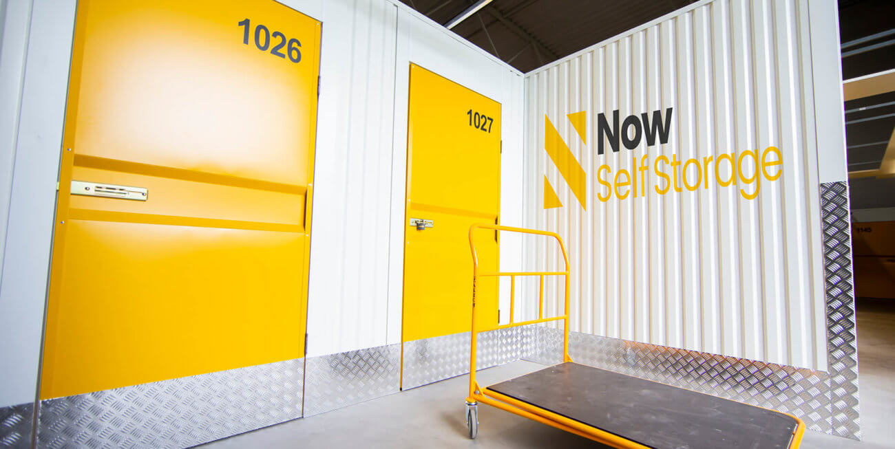 Exterior shot of storage containers with yellow doors and the Now Storage logo printed on
