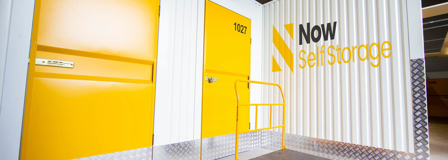 Exterior shot of storage containers with yellow doors and the Now Storage logo printed on