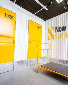 Exterior shot of storage containers with yellow doors and the Now Storage logo printed on