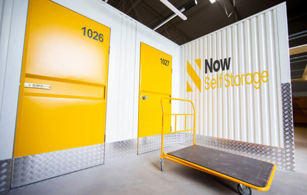 Exterior shot of storage containers with yellow doors and the Now Storage logo printed on