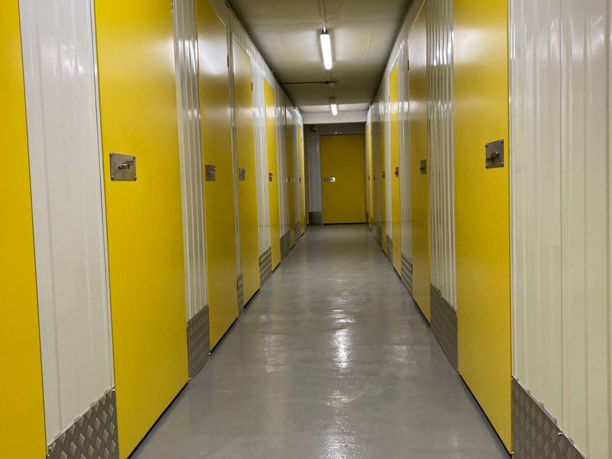 Indoor corridor of doors leading to storage containers.