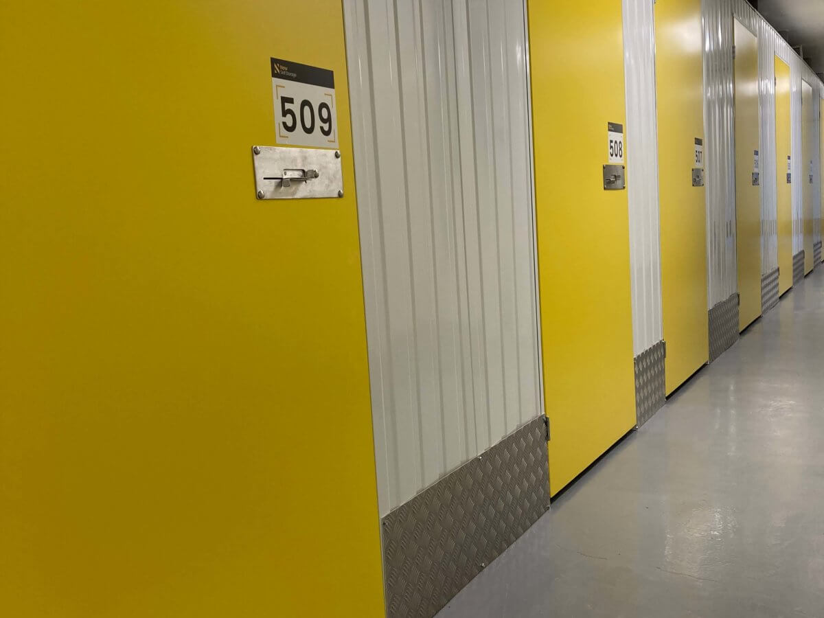 Indoor corridor of doors leading to storage containers.