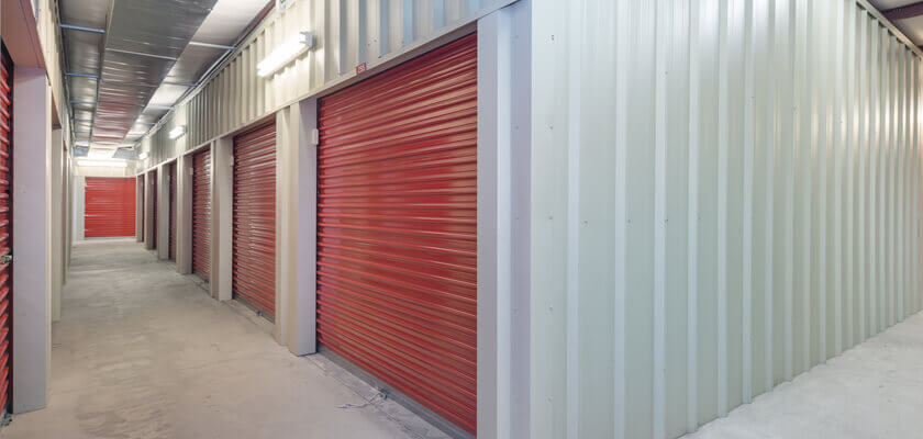 Image of a storage unit corridor with red shutter doors.