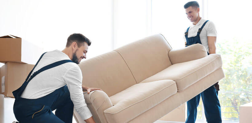 Two men moving sofa together.