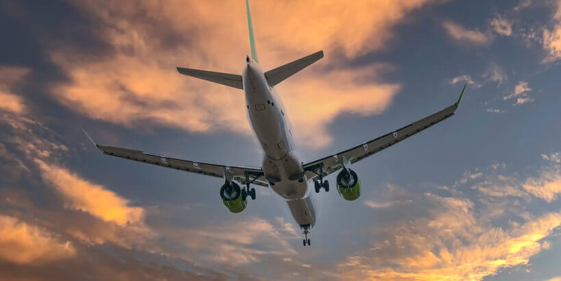 Image of plane in orange sunset sky. 