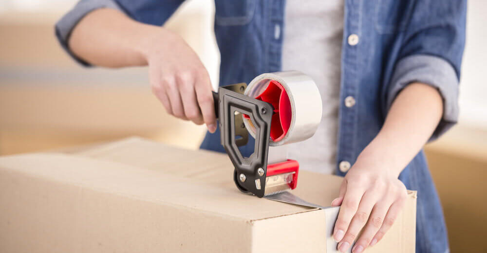 Image of a man putting sellotape over a cardboard box.