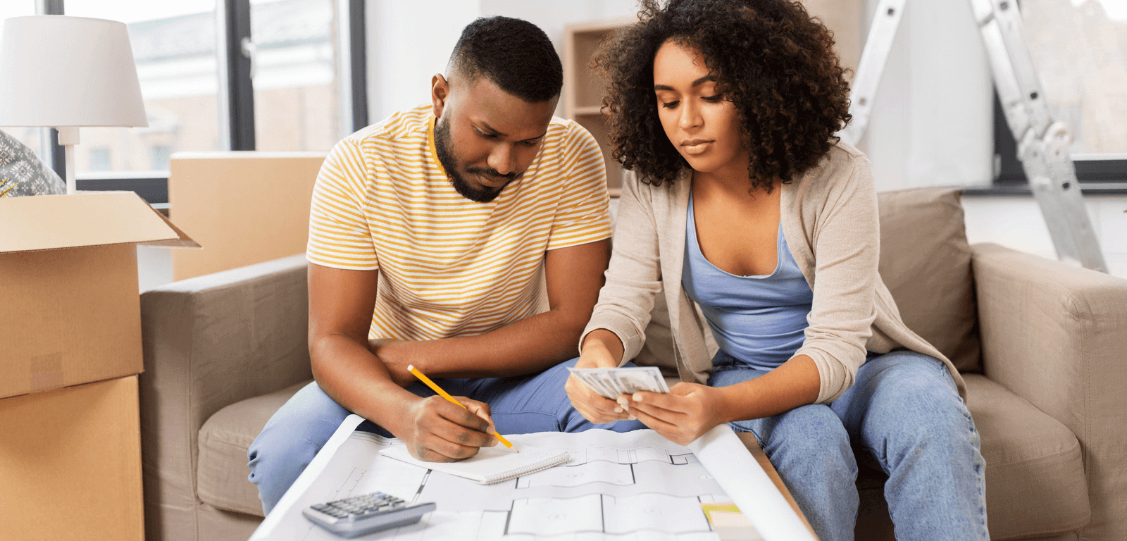A couple working out the costs of moving home with a large sheet of paper and a calculator.