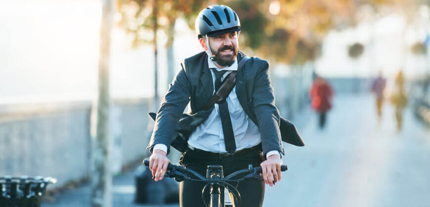 Image of a man in a suit commuting in a suit riding a bicycle. 