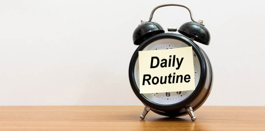 Image of a clock with a post-it sticker saying 'daily routine'.