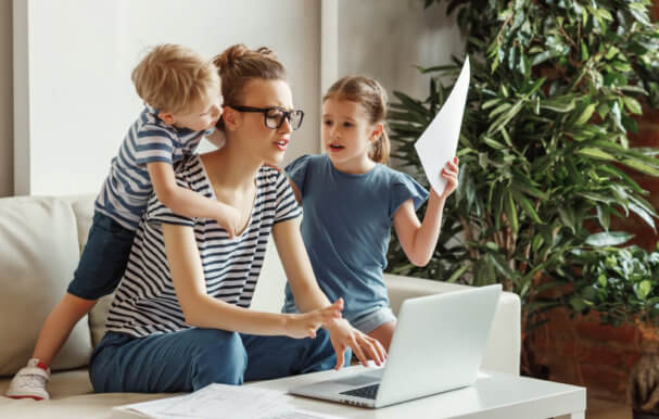 Image of a busy parent with two children asking questions and wanting attention.