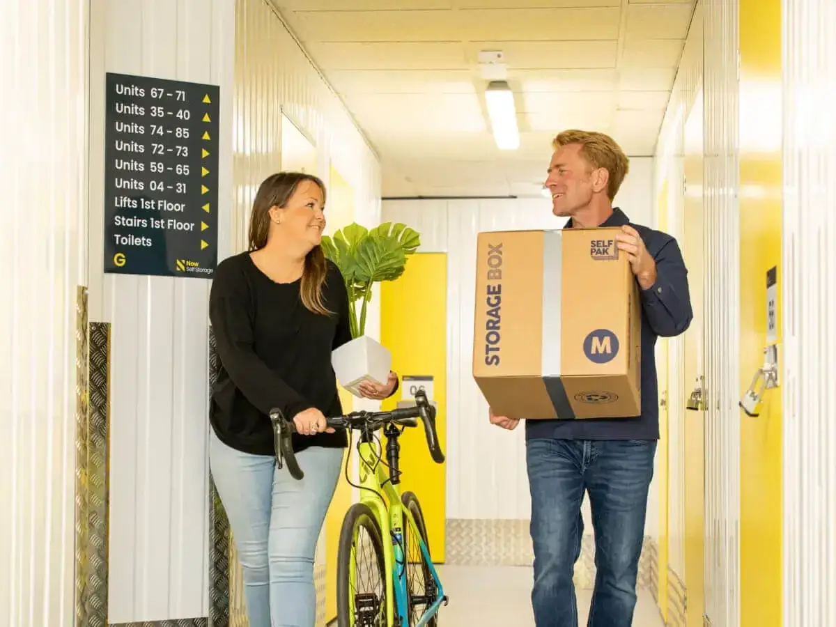 A man and woman carrying goods into a storage facility