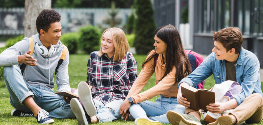 Students relaxing and chatting together on a lawn at university.