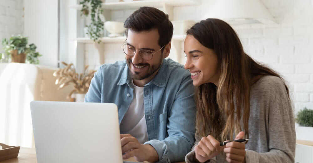 Image of a couple smiling together looking at a laptop.
