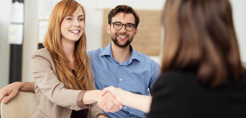 Image of happy customers shaking hands with employee.