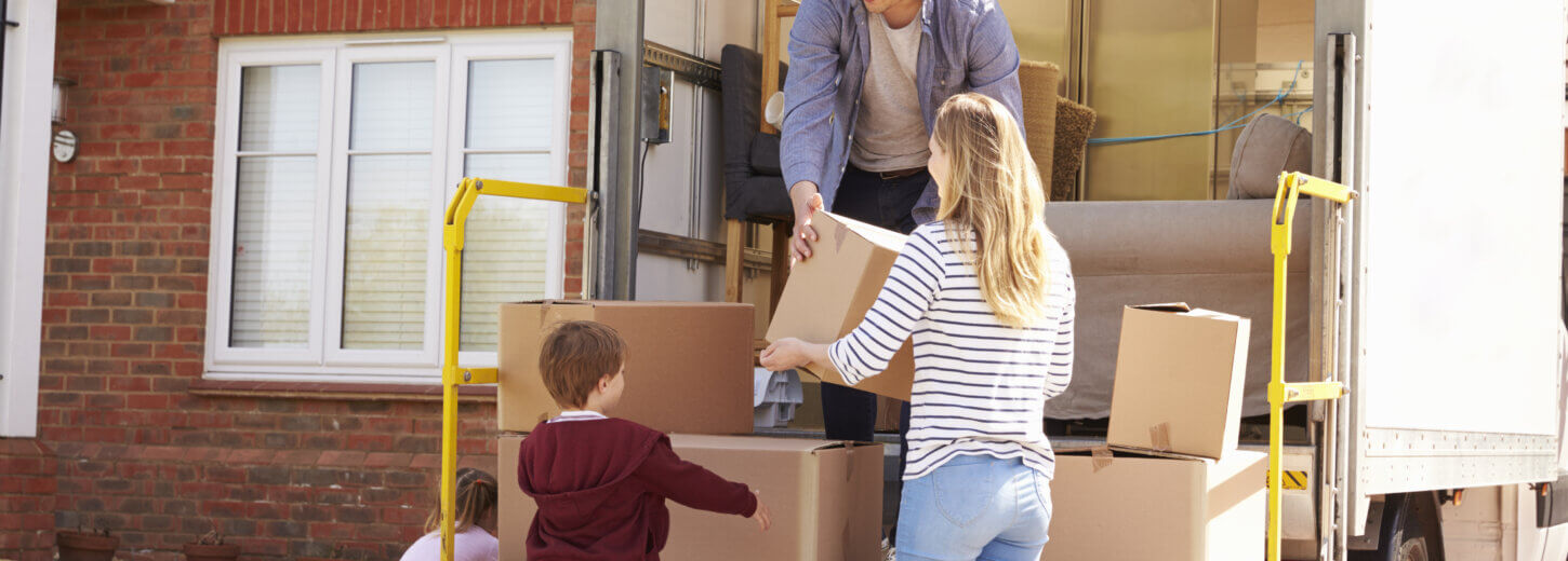 Family Unpacking Moving In Boxes From Self Storage Van