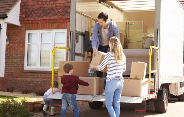 Family Unpacking Moving In Boxes From Self Storage Van