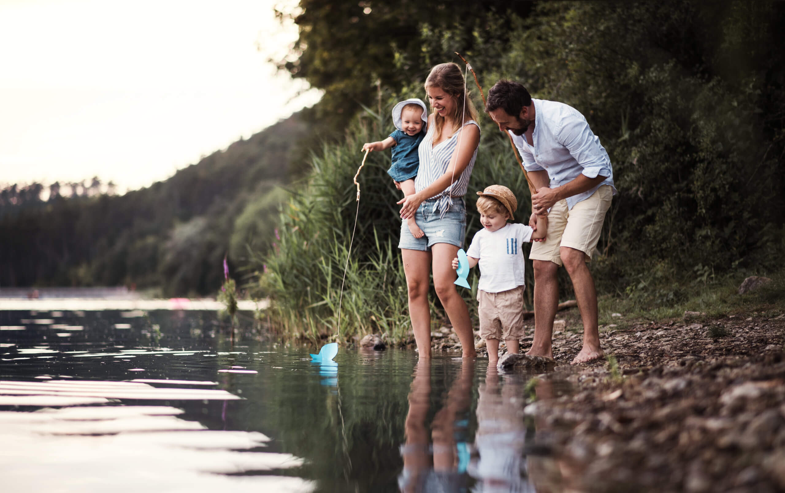 An image of a damily standing on the edge of some water and exploring the outdoors.