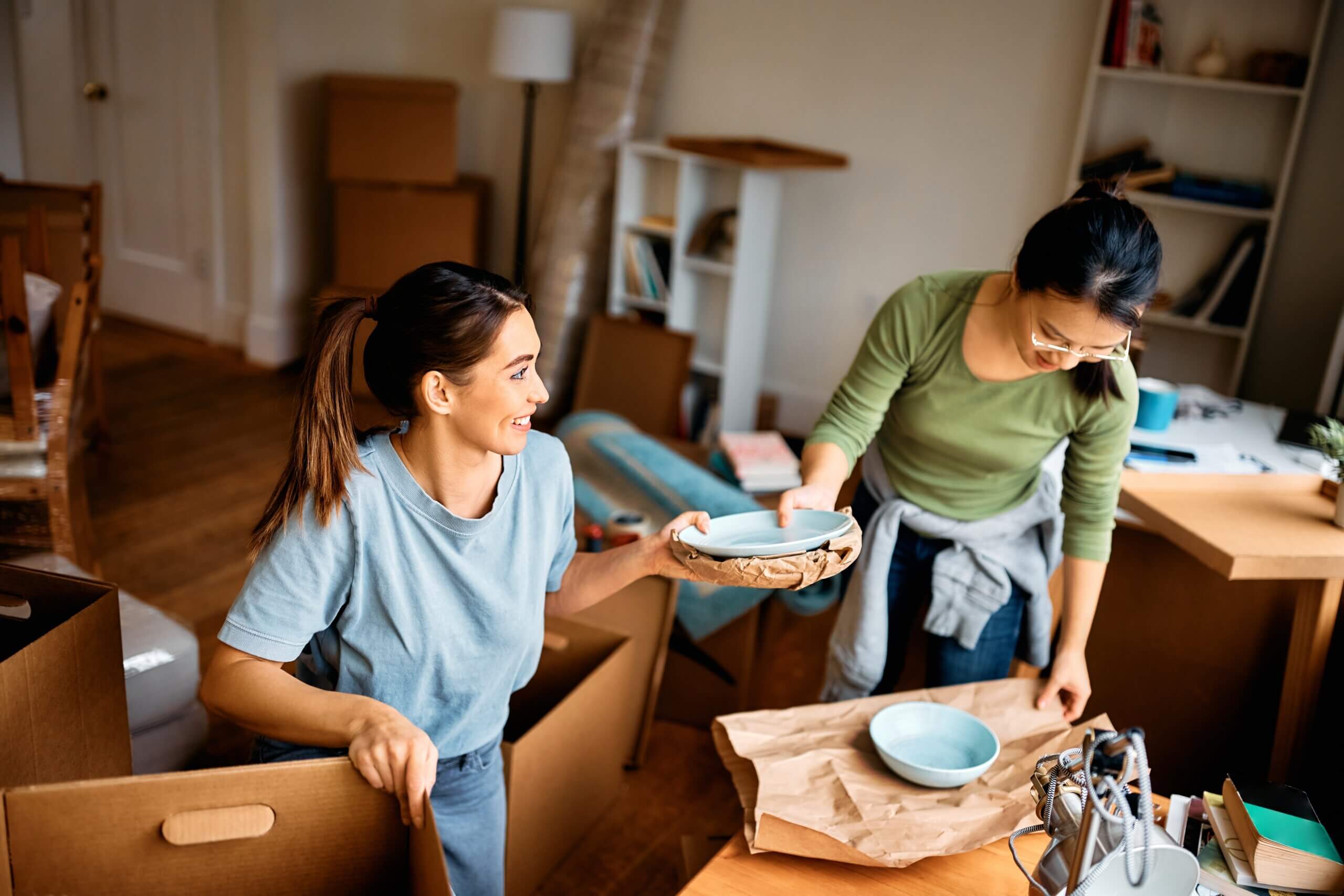 An image of two women carefully packing bowls ready for moving to their new house in Newbury.