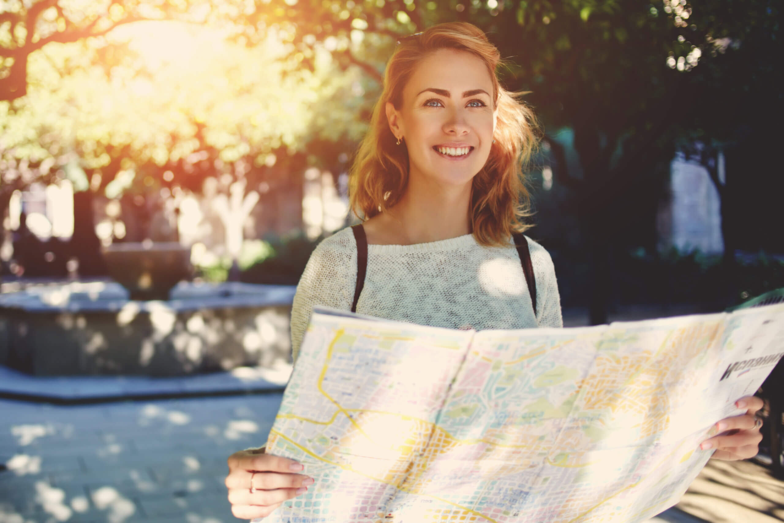 An image of a woman holding a map and smiling on her day trip from Newbury.